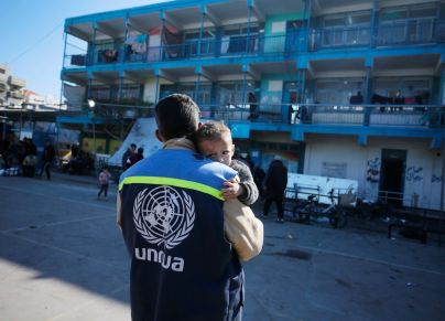 موظف في الأونروا يحمل طفلًا في إحدى المدارس التابعة للوكالة