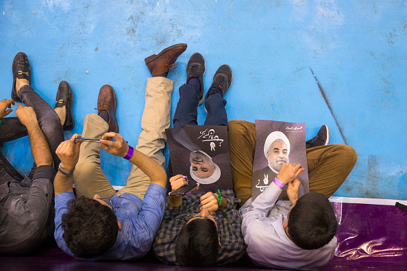 شباب إيرانيون يحملون صورة حسن روحاني (ماجدي سعيدي/ Getty)