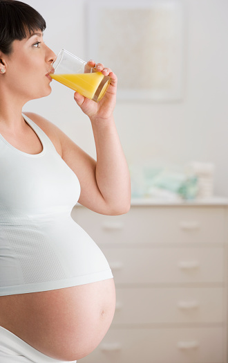 Pregnant Hispanic woman drinking orange juice