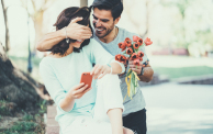 Young man surprising his girlfriend with bouquet of tulips