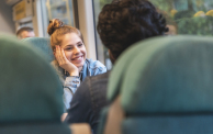 Portrait of happy young woman travelling by train with her friend