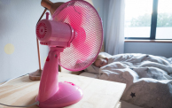 Girl sleeping in bed with a pink fan blowing cool air over her