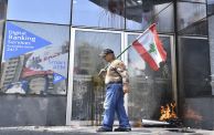(Getty) لبناني يحمل علم بلاده أمام بنك تعرض للتخريب