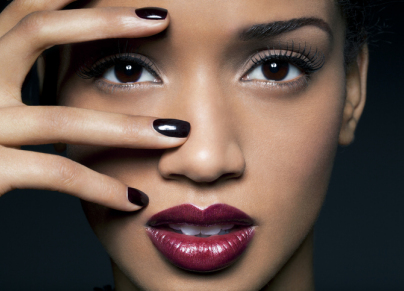 Young woman with red lips and black nail polish.