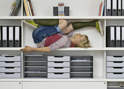 young woman stretching in office shelves