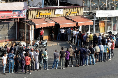 People line up in front of a bakery to buy bread in Lebanon's southern city of Sidon