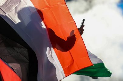 رجل خلف علم فلسطين يحمل هاتفًا