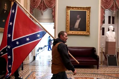 مناصر لترامب يحمل علم الكونفدرالية الأمريكية خلال اقتحام الكونغرس (رويترز)