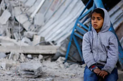 طفلة فلسطينية أمام أنقاض منزل في رفح (رويترز)