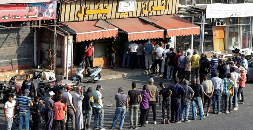 People line up in front of a bakery to buy bread in Lebanon's southern city of Sidon