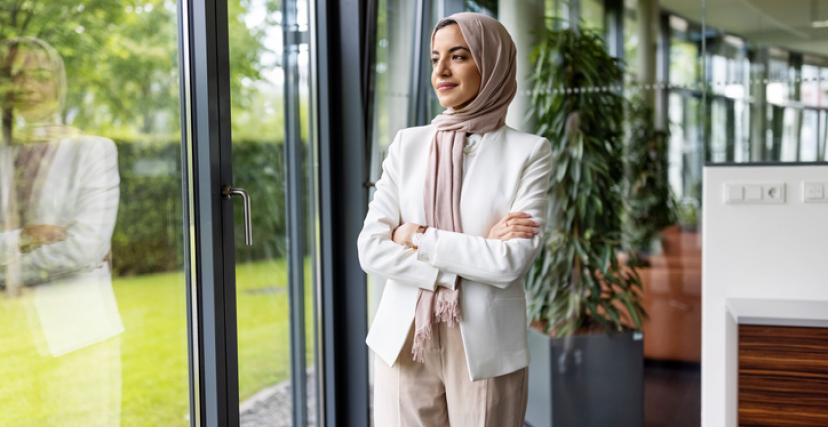 Muslim woman standing in office and looking outside