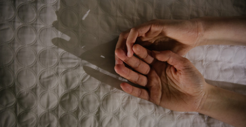 Close-Up Of Hands On Bed