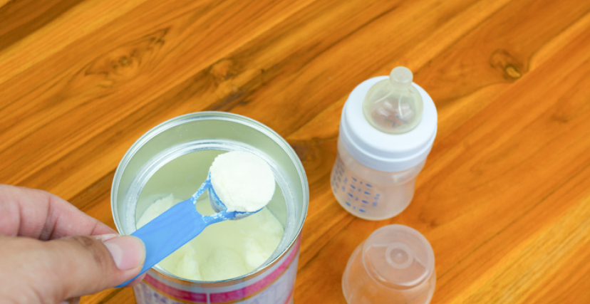 New parents Powder milk and blue spoon on light background close-u