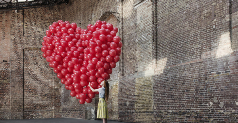 Woman in warehouse with heart made of balloons