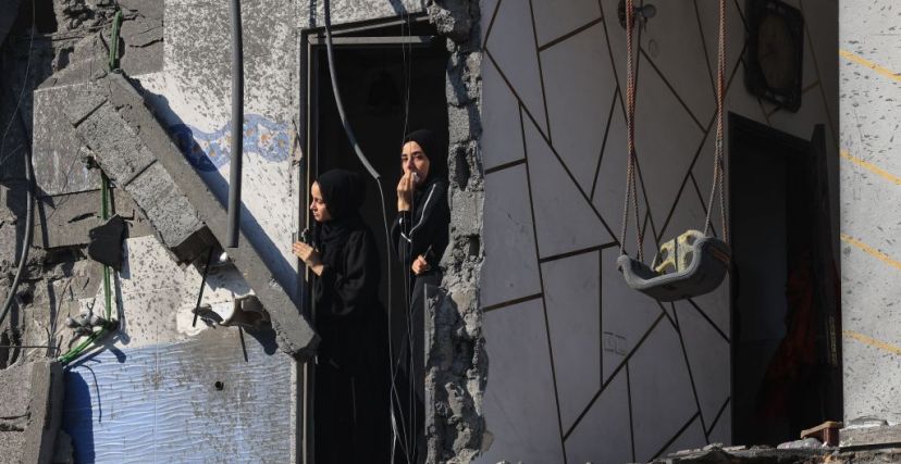 نساء فلسطينيات في مبنى متضرر يشاهدن فرق الإنقاذ أثناء بحثها عن ناجين تحت الأنقاض بعد قصف إسرائيلي