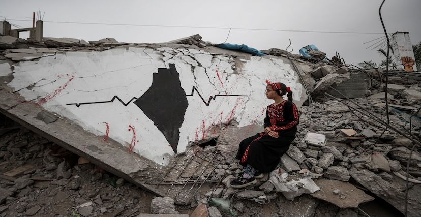 طفلة فلسطينية بجوار أنقاض غرافيتي في غزة 