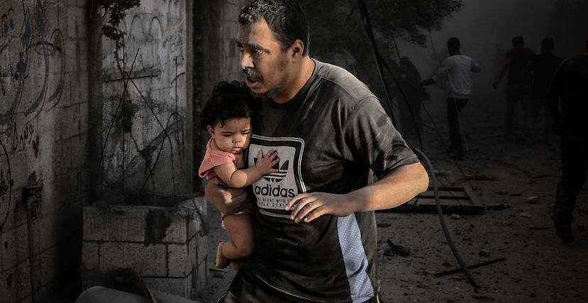 فلسطيني يحمل ابنته بعد غارة إسرائيلية على مخيم المغازي