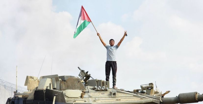 شاب يرفع العلم الفلسطيني فوق دبابة إسرائيلية يوم السابع من تشرين الأول/أكتوبر