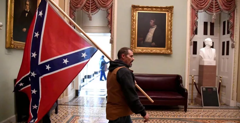 مناصر لترامب يحمل علم الكونفدرالية الأمريكية خلال اقتحام الكونغرس (رويترز)