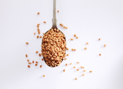 High Angle View Of Fenugreek Seeds In Spoon Over White Background