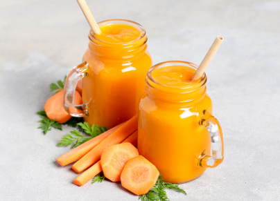 Carrot smoothie in a glass jar with a bamboo straws on a light...