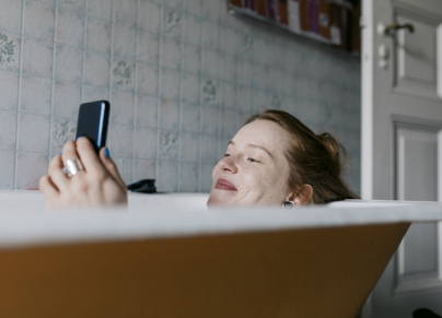 woman looking at phone in bathtub