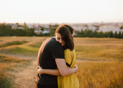 Young couple is hugging in nature at sunset