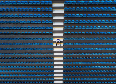 Aerial image looking down on one person sitting amongst empty seats 