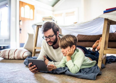 a father using a tablet on the floor with his son