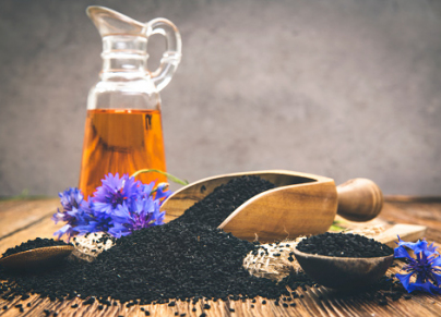 Black cumin seeds essential oil with wooden spoon and shovel on...