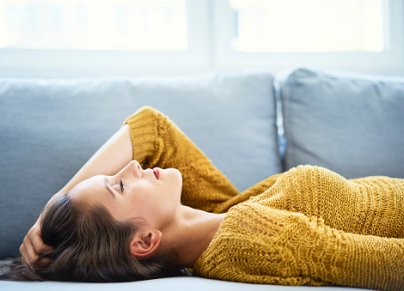 Young woman lying on sofa with eyes closed and relaxing