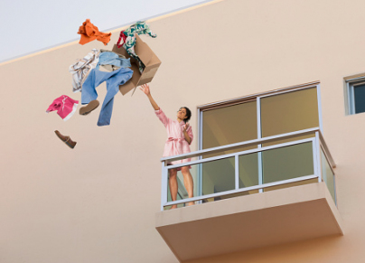 Mixed race woman throwing clothes off balcony