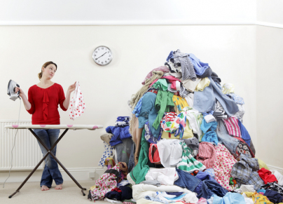 woman ironing next to very large pile of clothes