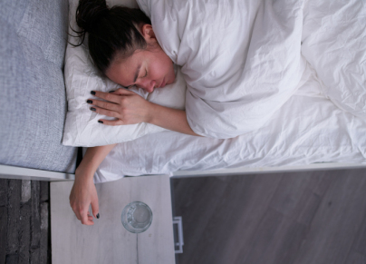Woman sleeping near bedside table with water